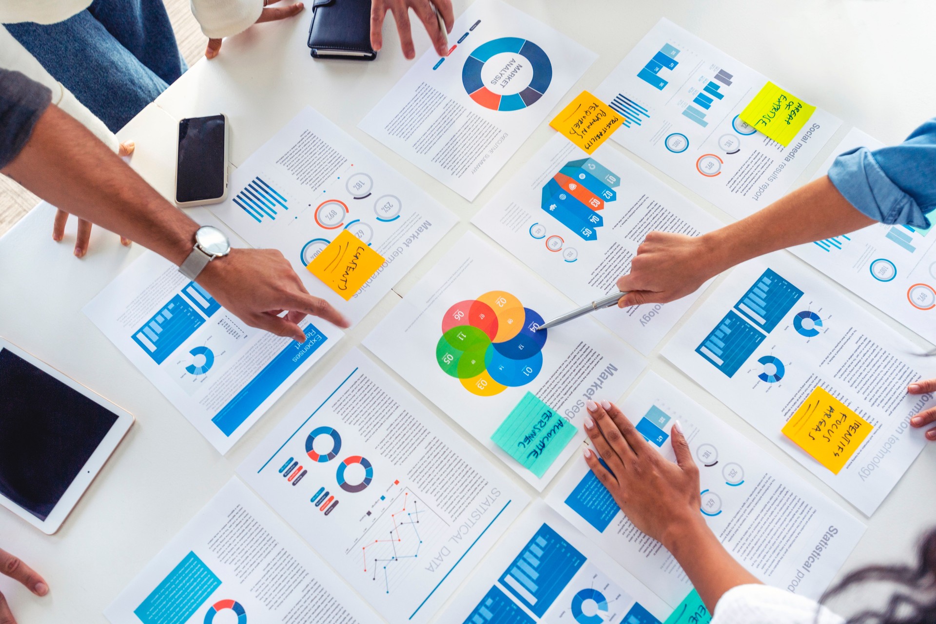 Paperwork and hands on a board room table at a business presentation or seminar.